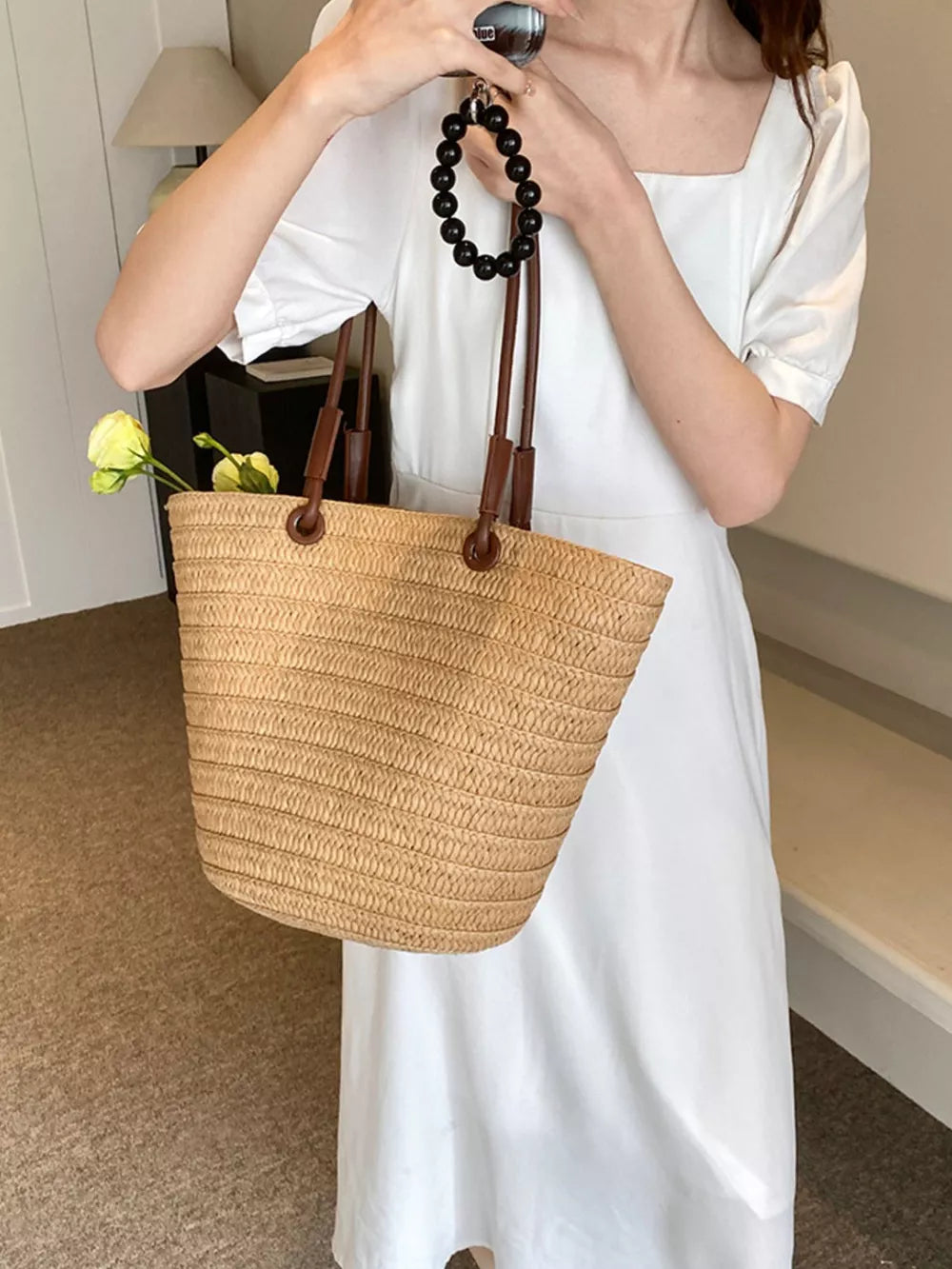 Natural straw woven large shoulder bag in khaki with leather straps and black beaded handle detail.