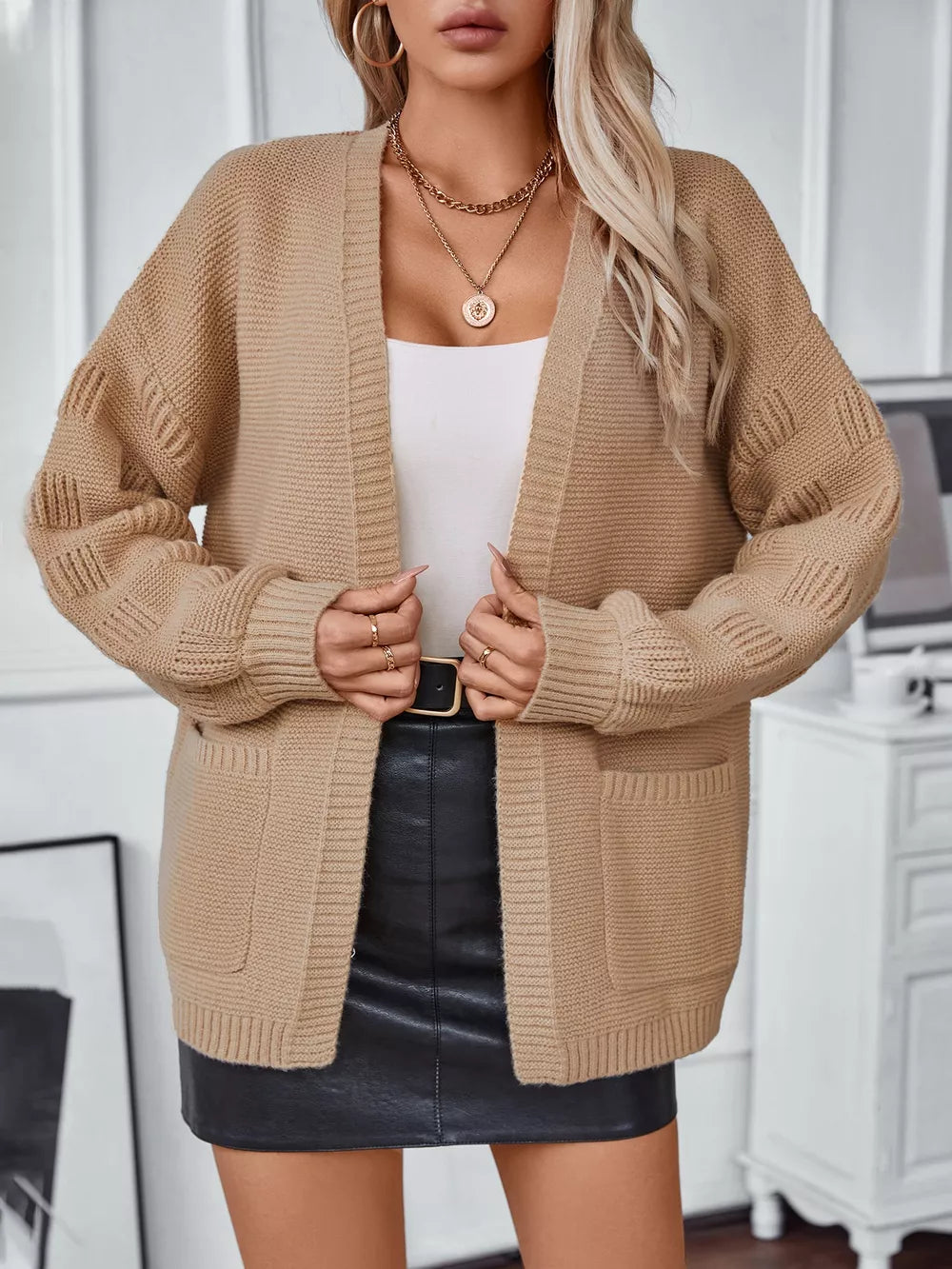 Chunky knit camel open-front cardigan with pockets and textured sleeves.