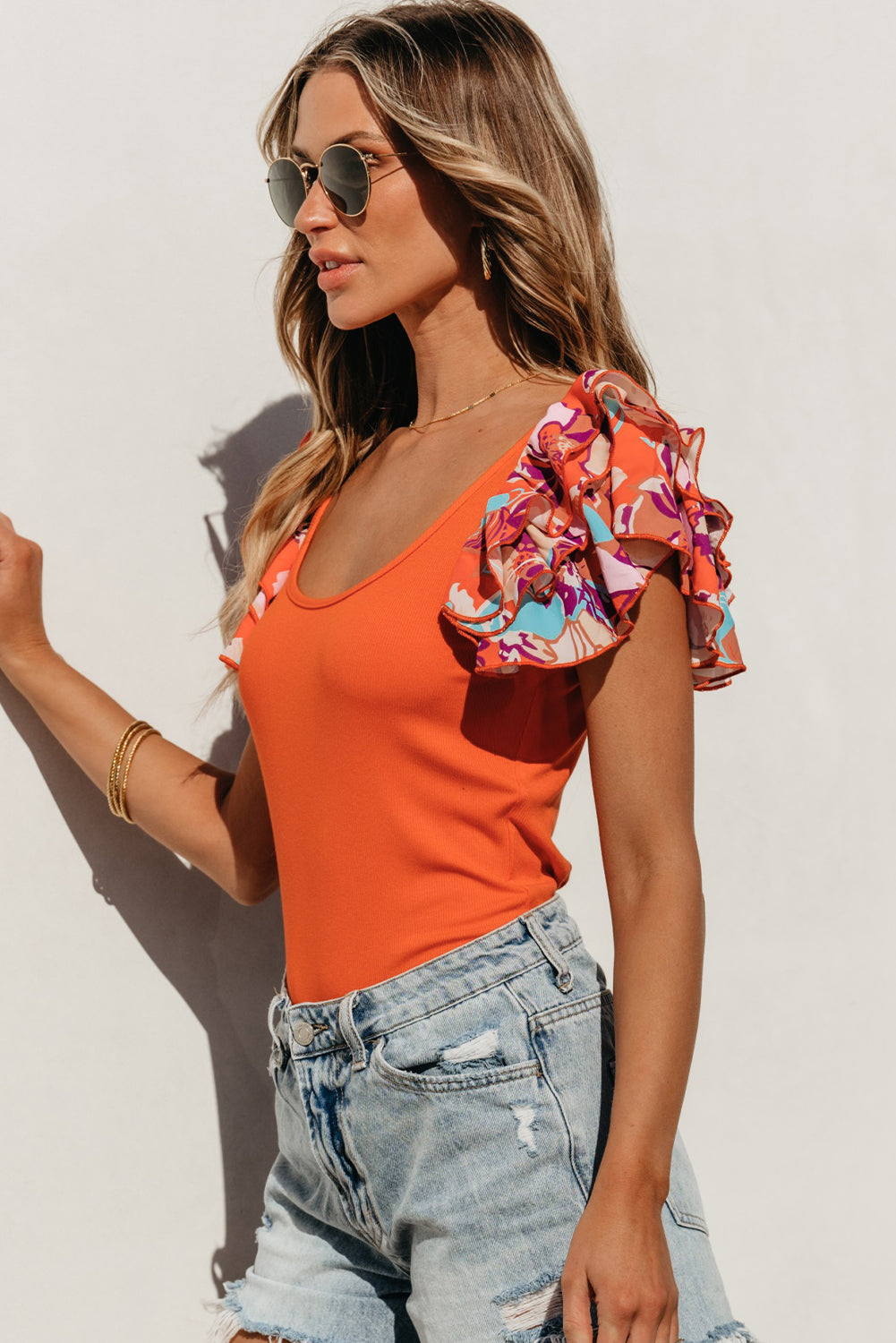 Orange ribbed bodysuit with floral ruffle sleeves and scoop neck.