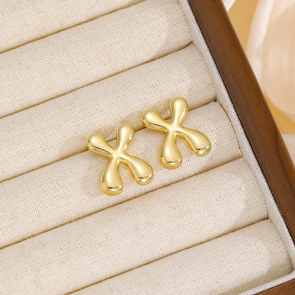 Gold sculpted stud earrings with a bubble-like, abstract alphabet design.