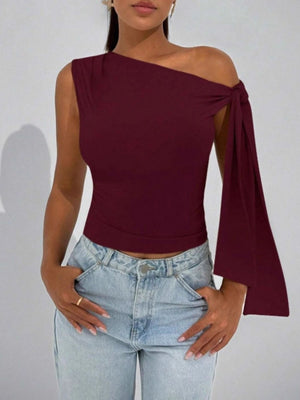 Burgundy asymmetrical tie detail blouse with one sleeve and one sleeveless arm.