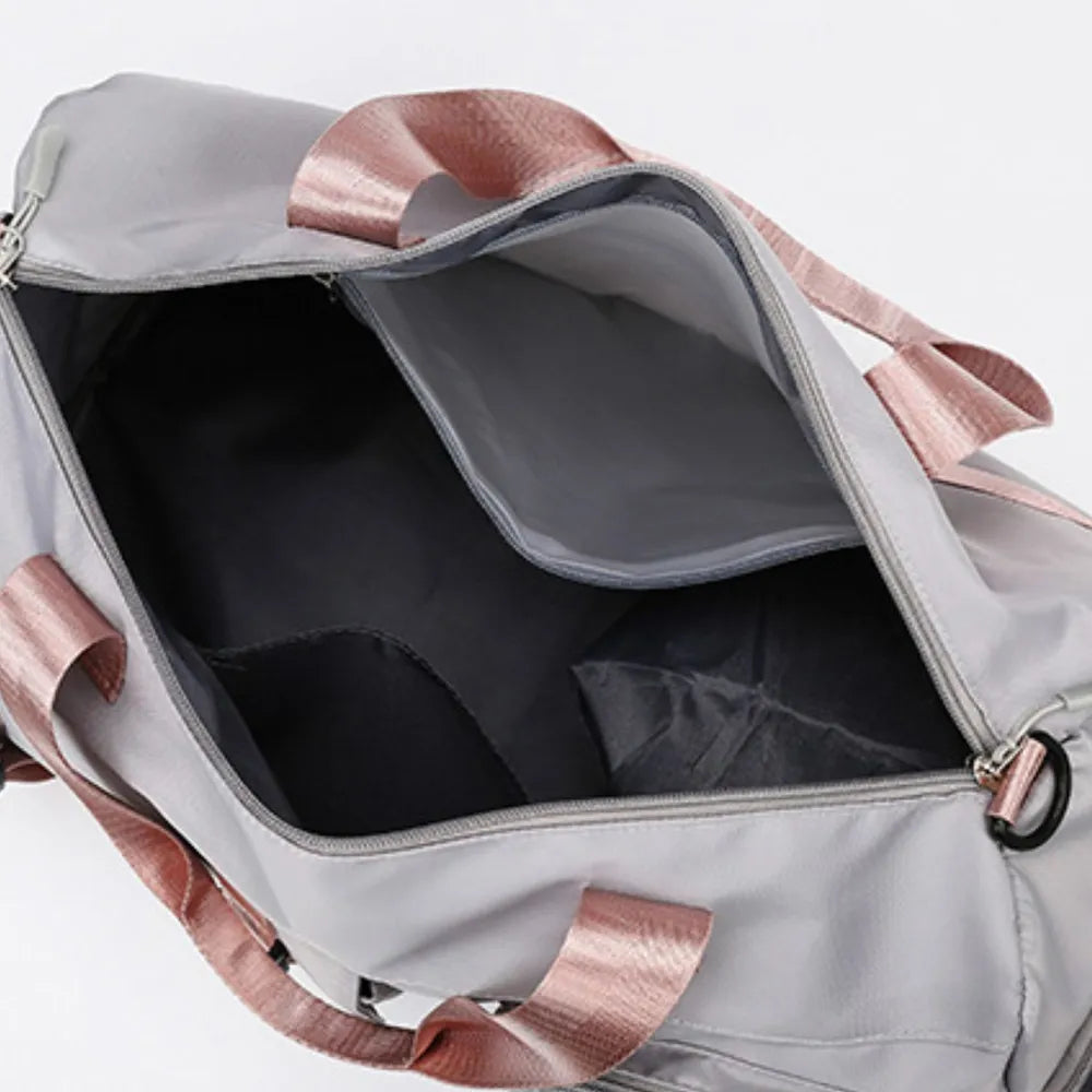 Gray gym duffel bag with dusty pink straps and interior pockets.