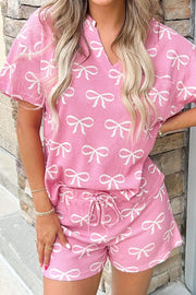Pink ribbed lounge set with all-over white bow print, V-neck top and drawstring shorts.