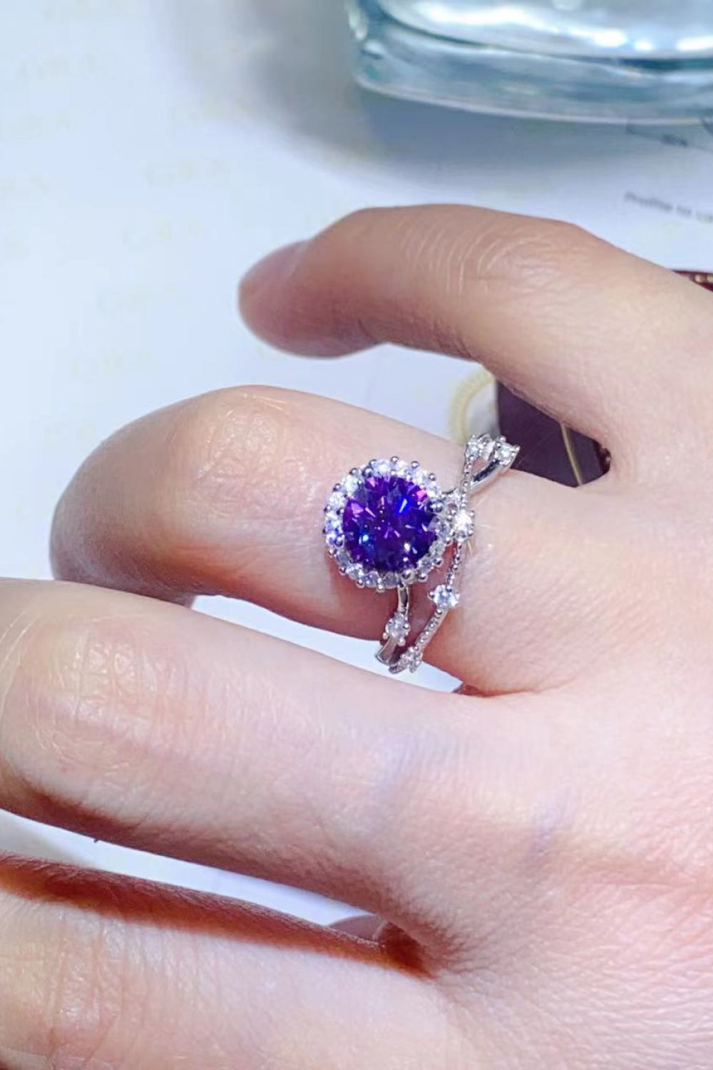 Purple moissanite halo engagement ring set with diamond accents on a silver band.