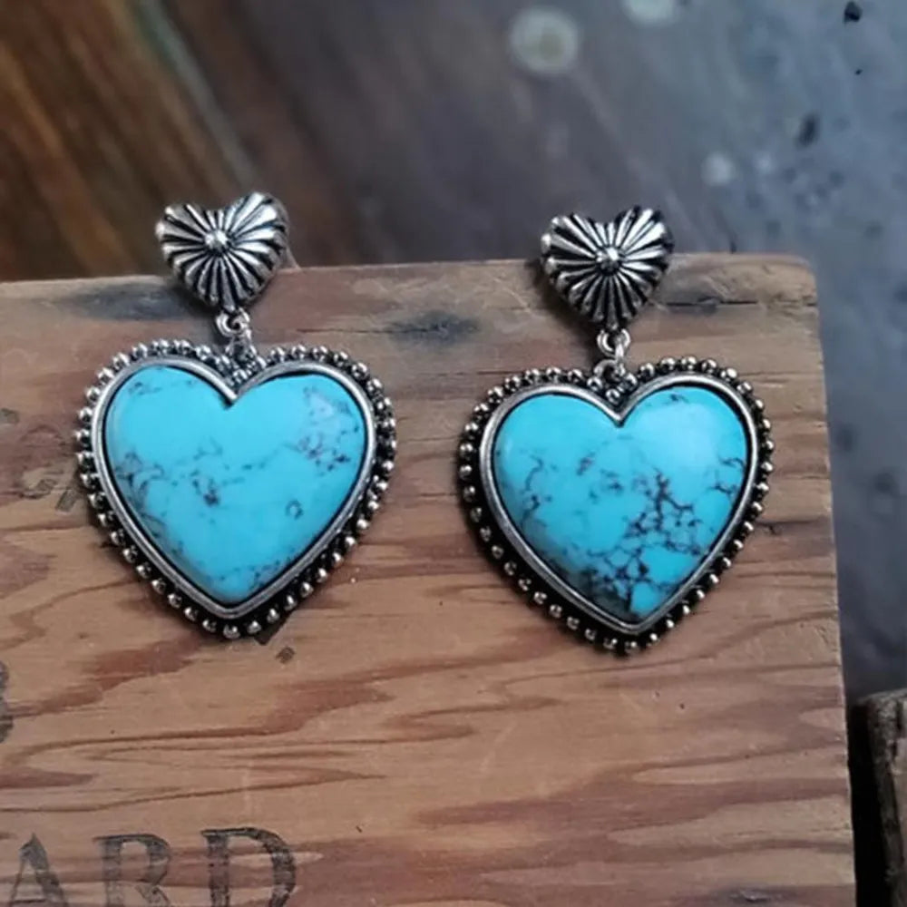 Turquoise heart stone drop earrings with silver beaded trim and sunburst tops.