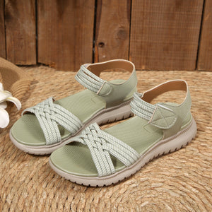Green woven strap open-toe flat sandals with adjustable ankle straps.