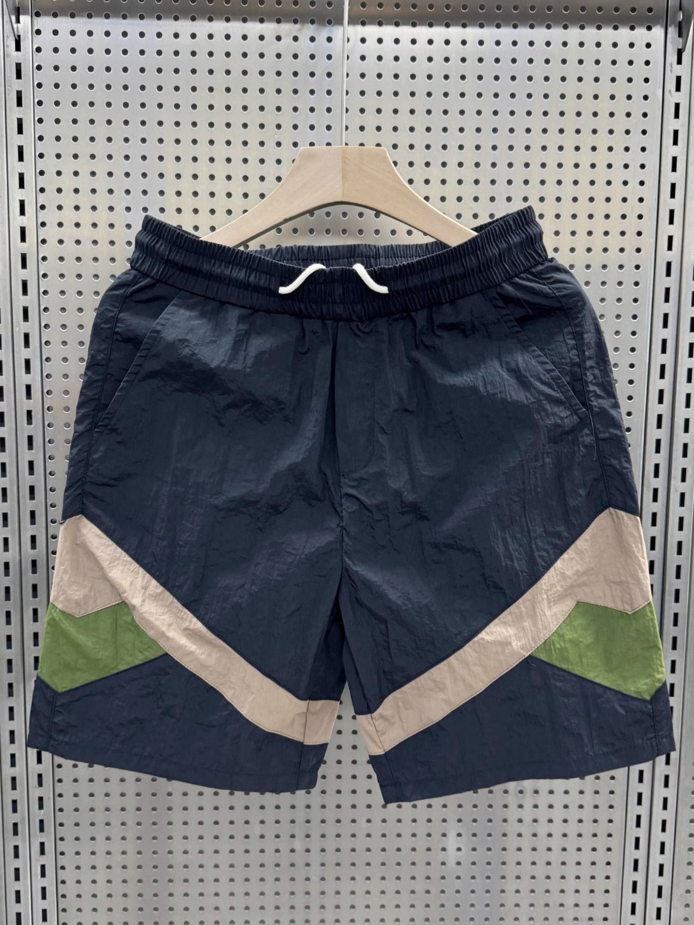 Men's boxer shorts in dark blue with beige and green color block accents.