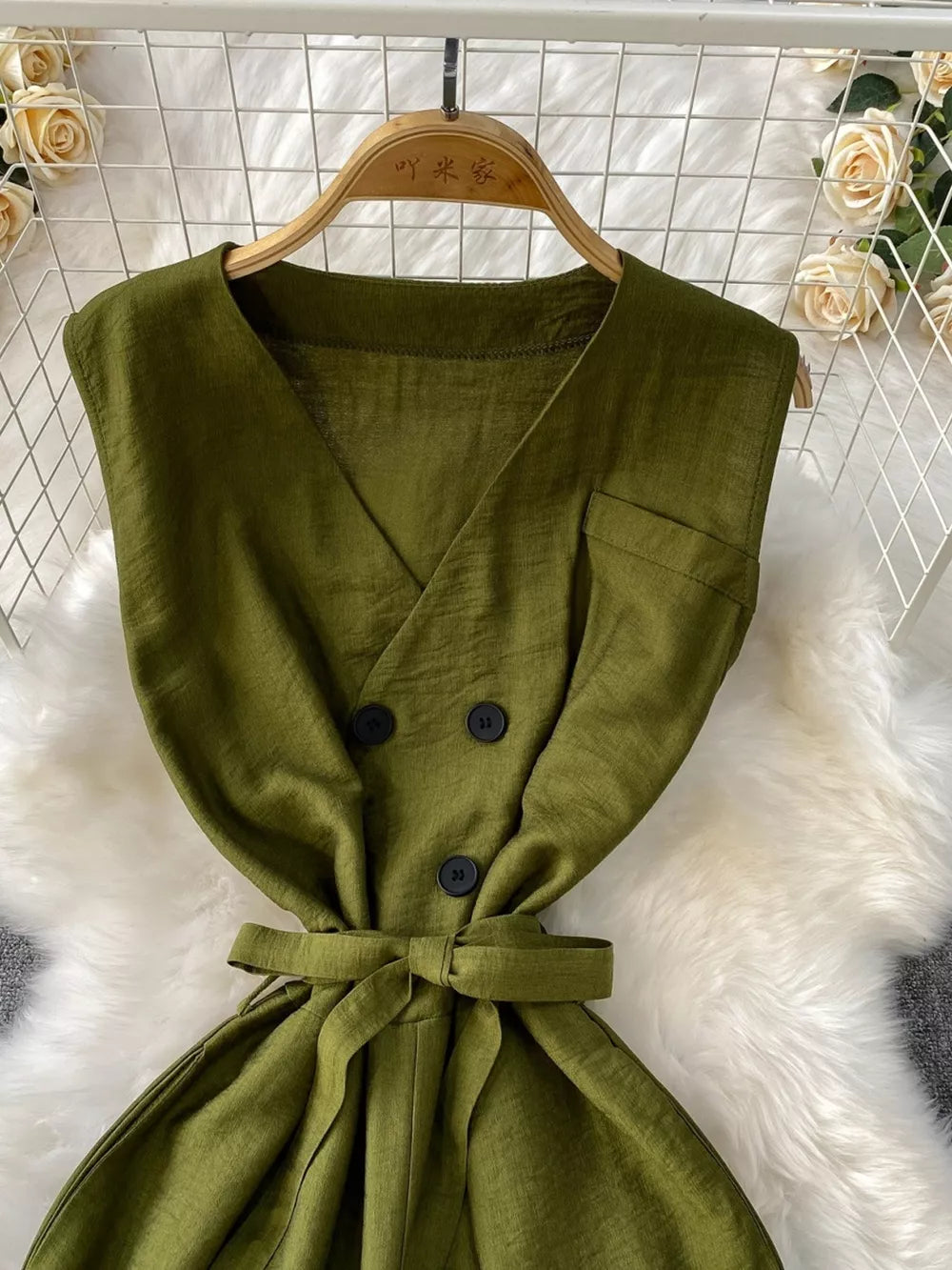Green V-neck wide leg jumpsuit with double-breasted buttons and tie waist.