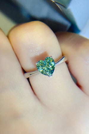 Green heart moissanite solitaire ring with a silver band.