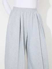 Light gray pleated drape palazzo trousers with elastic waistband and wide leg.