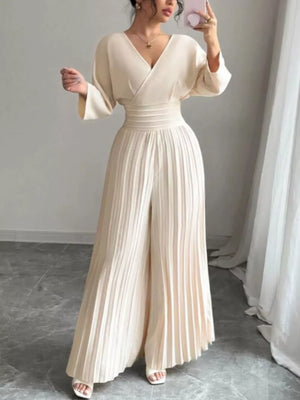 Elegant beige pleated wide-leg jumpsuit with cinched waist and V-neck.