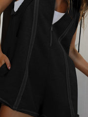 Black sleeveless hooded romper with raw edges and a zip front.