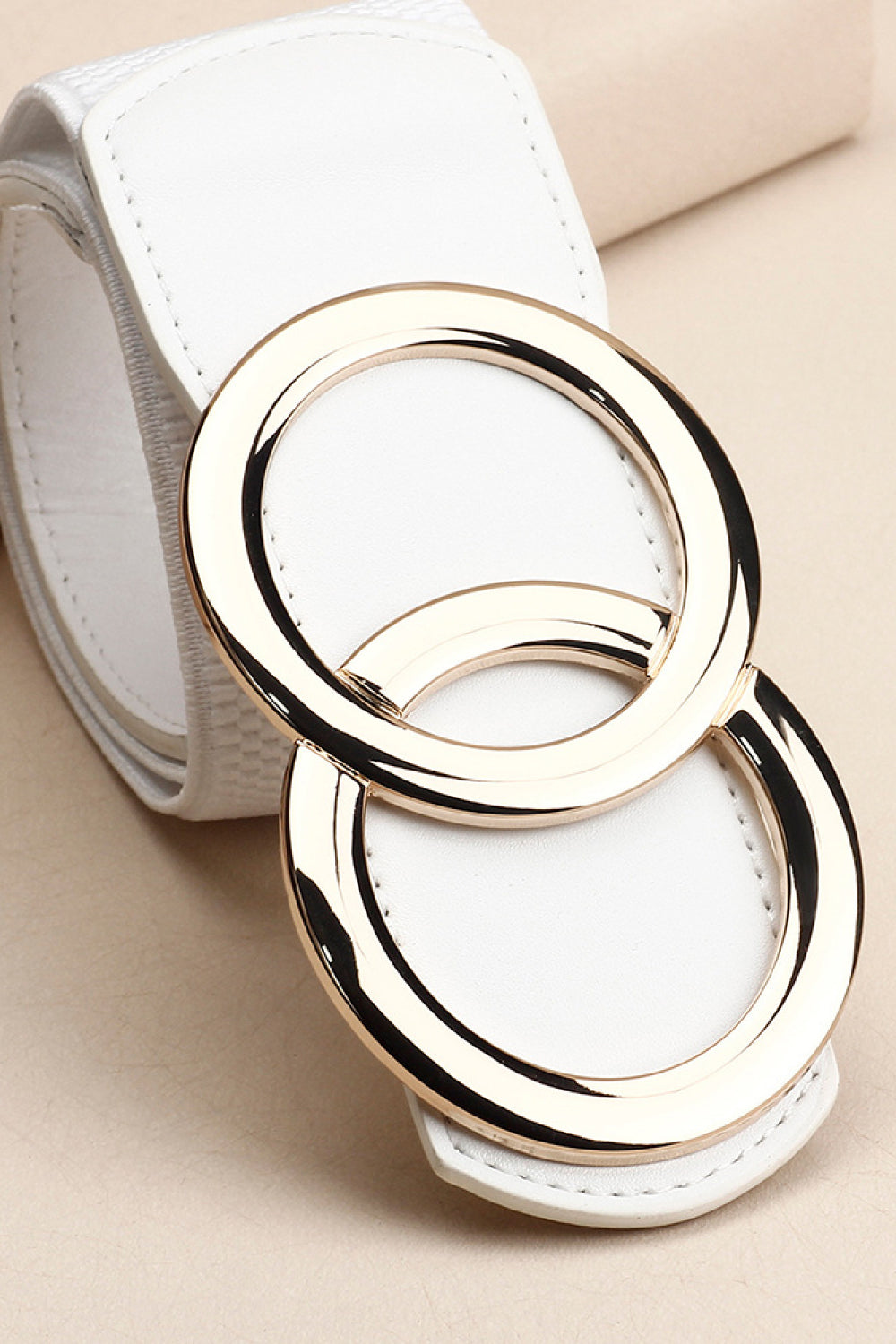 White stretch belt with interlocking gold rings and textured detail