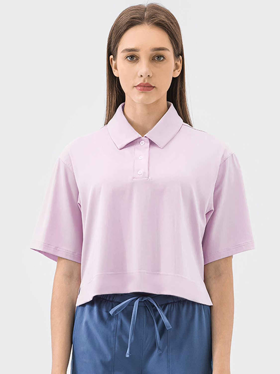 Cropped blush pink polo shirt with short sleeves and a button placket.