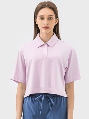 Cropped blush pink polo shirt with short sleeves and a button placket.