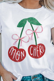 White graphic t-shirt with red cherries and pink bows, featuring "Mon Chéri" text.