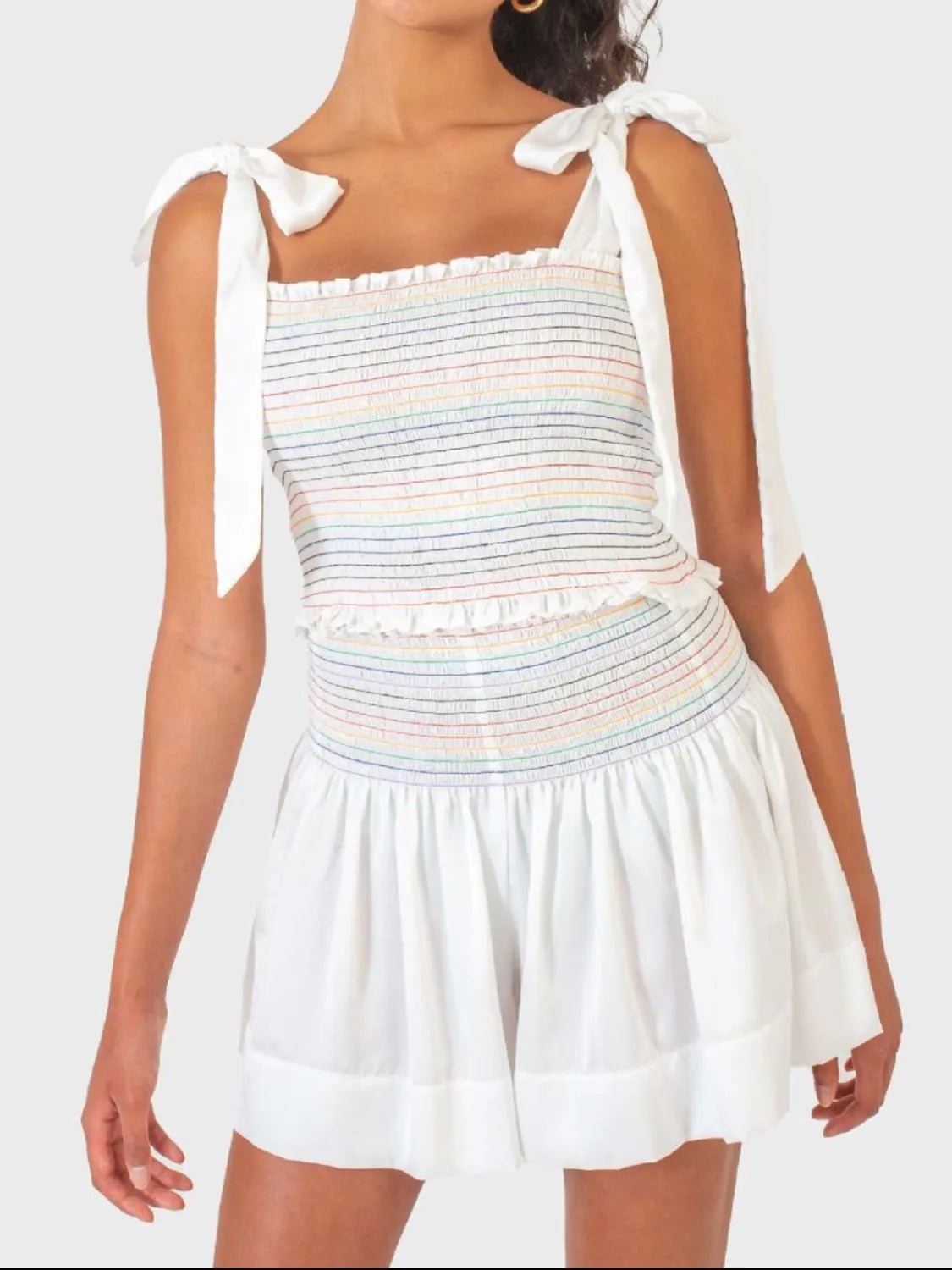 White outfit set with rainbow smocked bodice and tie straps, paired with flowy shorts.
