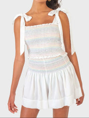 White outfit set with rainbow smocked bodice and tie straps, paired with flowy shorts.