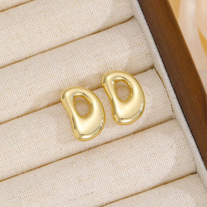 Gold sculptural stud earrings in the shape of the letter D.