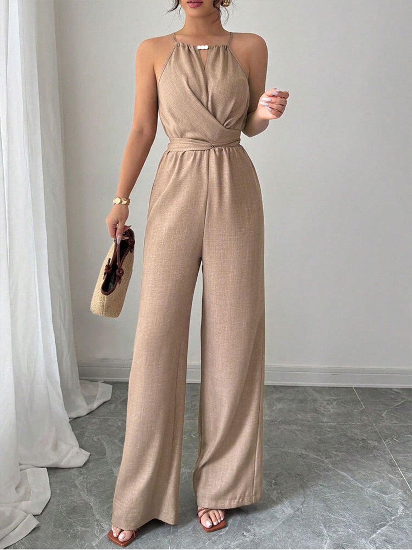 Halter neck wide leg jumpsuit in beige with a wrap bodice and tie waist.