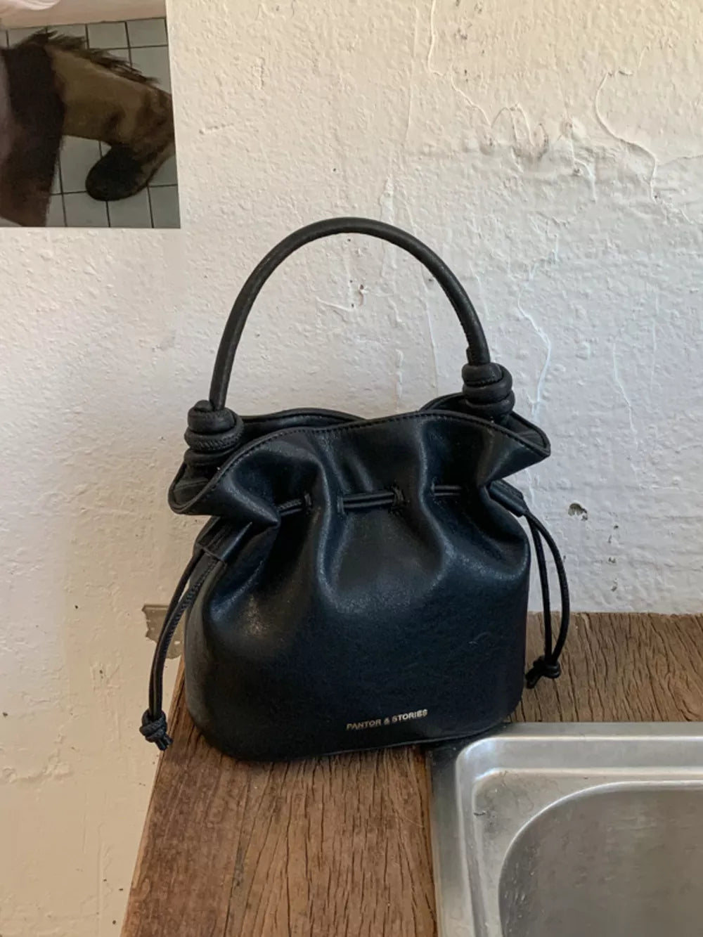 Black pu leather cinch-top crossbody bag with knotted handle detail
