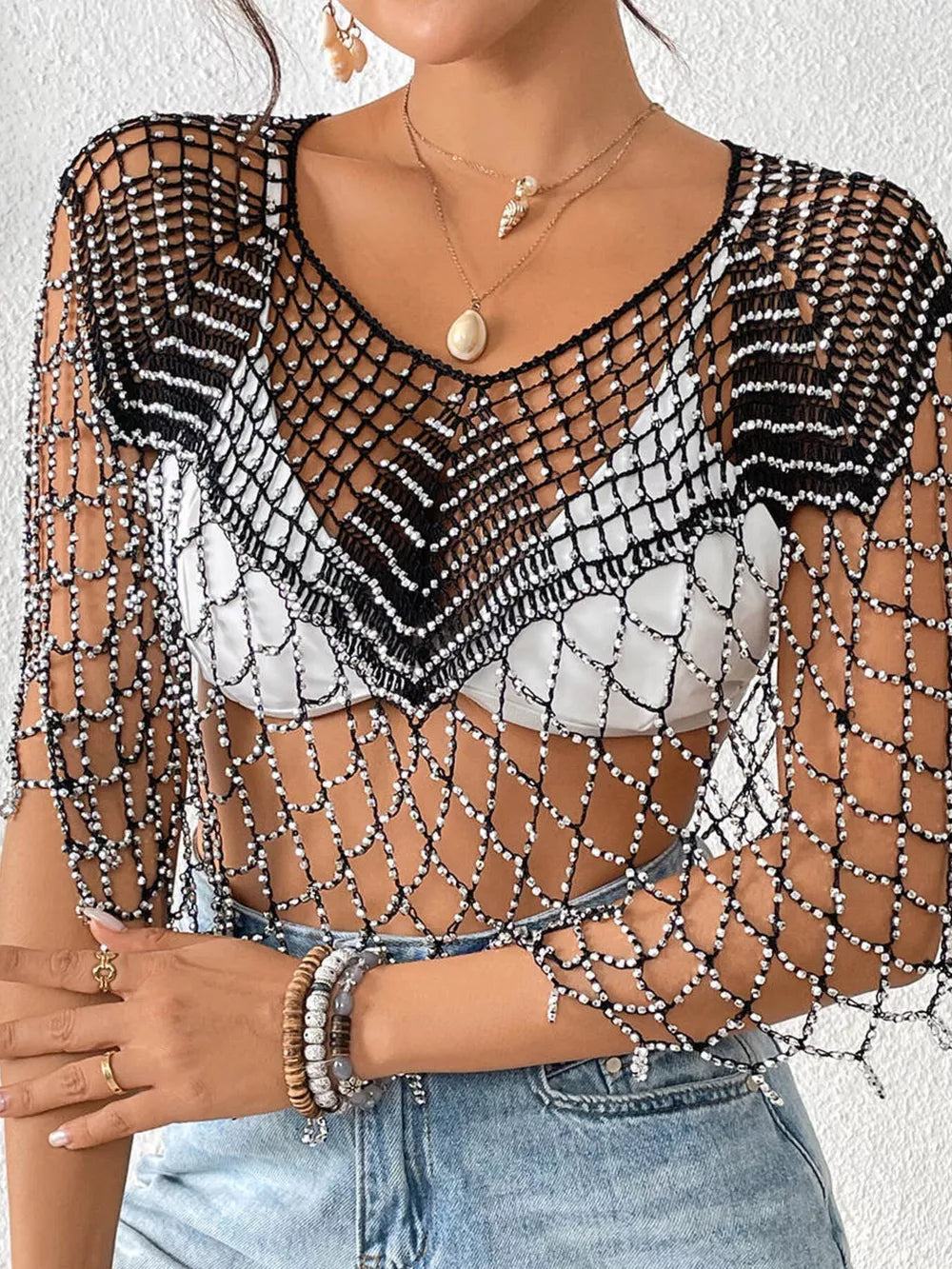 Black crochet cardigan with beaded detail and V-neck, styled over a white top.