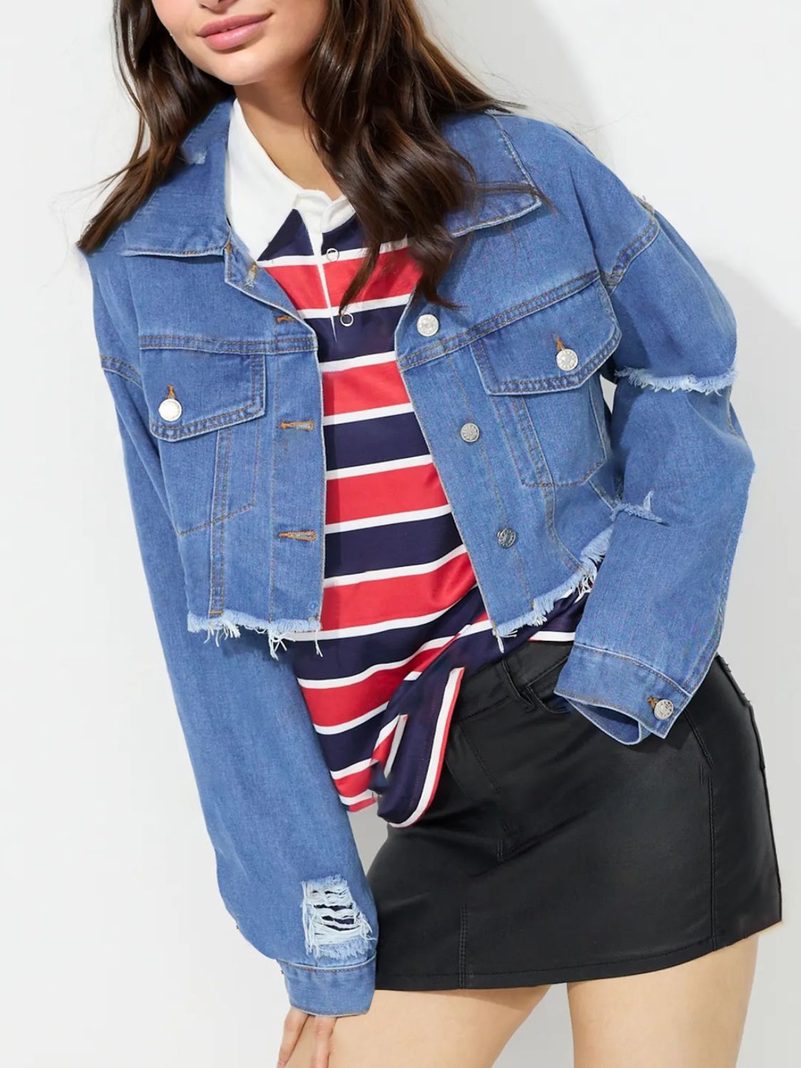 Medium wash denim trucker jacket with raw hem and distressed details.