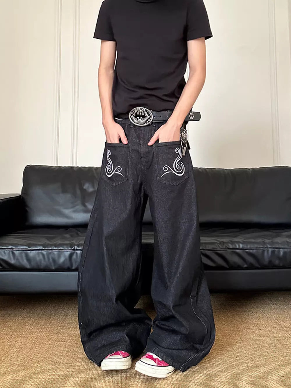 Men's dark wash wide-leg jeans with white embroidered pocket details.
