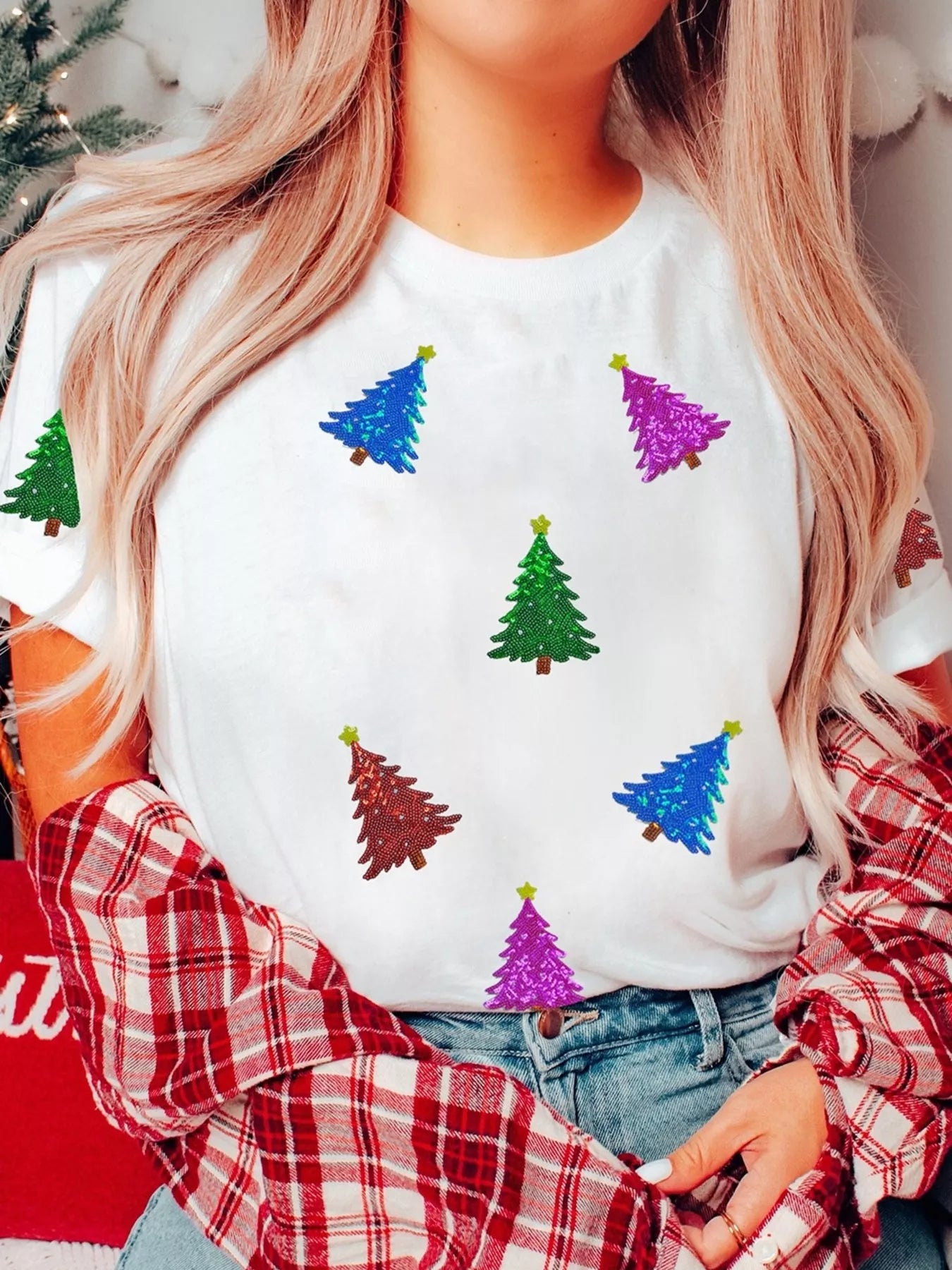 White t-shirt with scattered sequin Christmas trees in blue, green, purple, and red.