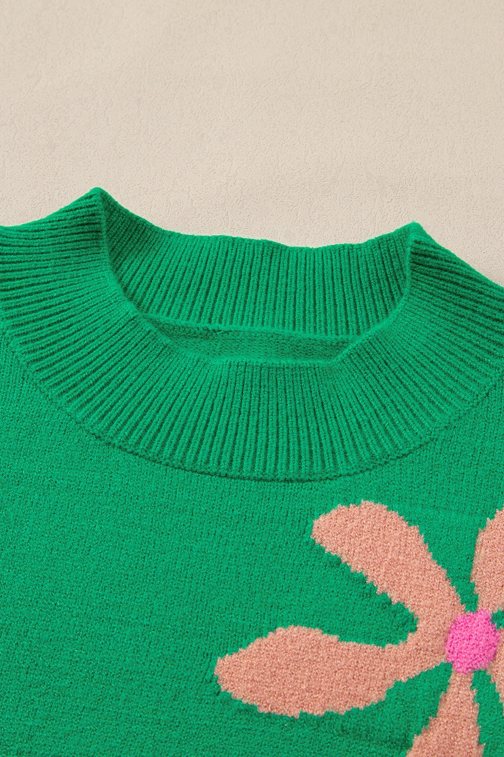 Green knit sweater with a large floral print and ribbed crew neck.