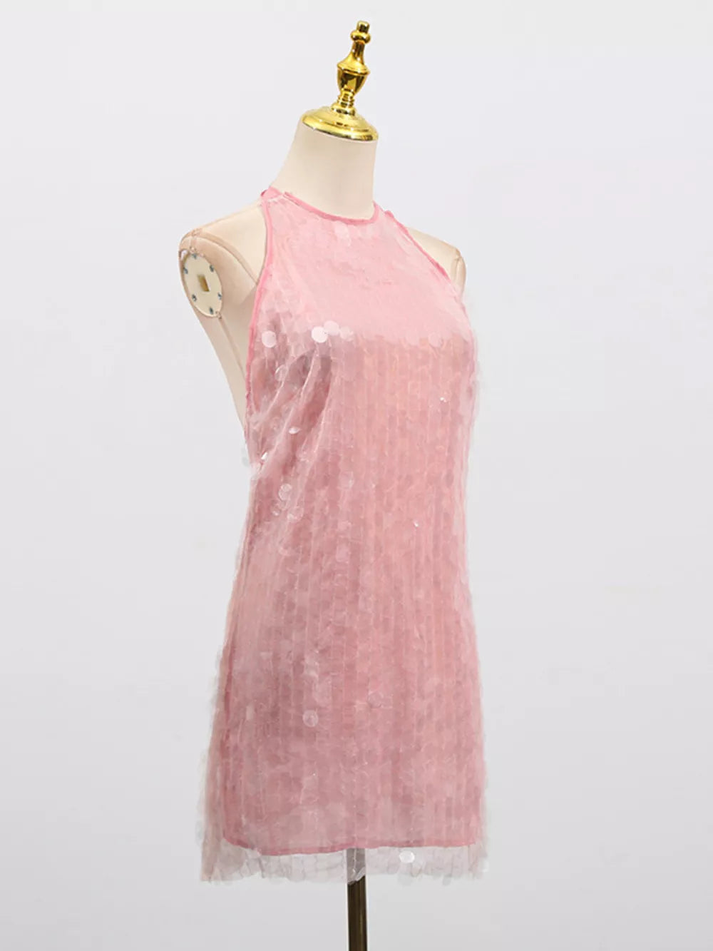 Pink iridescent sequin halter mini dress with sheer overlay and ruffled hem.