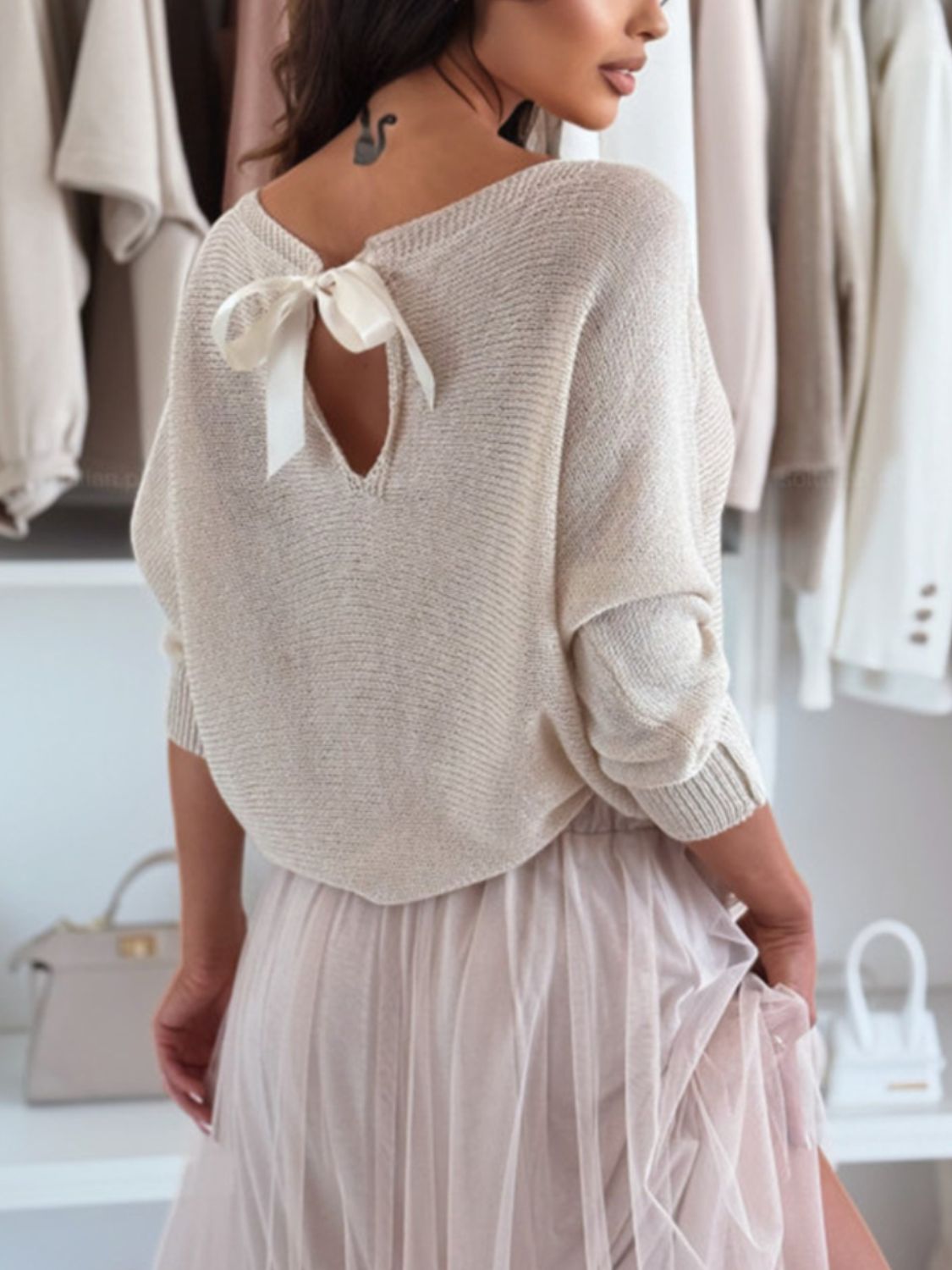 Cream knit sweater with batwing sleeves and a bow-back cutout detail