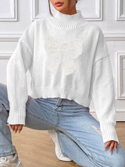 White turtleneck knit sweater with lace bow appliqué detail.