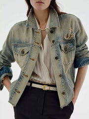 Distressed light wash denim trucker jacket with button-up front and frayed details.