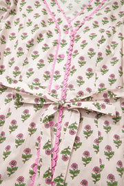 Floral V-neck midi dress in blush pink with pink scalloped trim and button front.