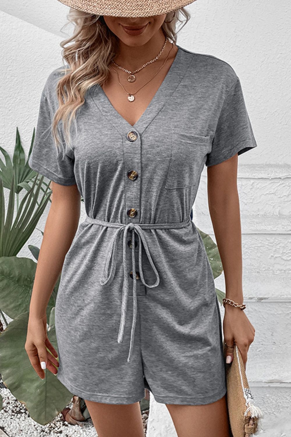 Gray Dawn button-front romper with V-neck, short sleeves, and waist-tie detail.
