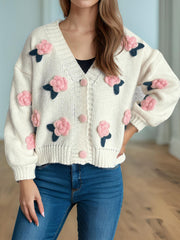 Cream knit cardigan with pink embroidered rose appliqués and buttons.