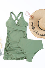 Sage ruched halter swim dress with crisscross bodice and ruffled hem, paired with high-waisted bottoms.