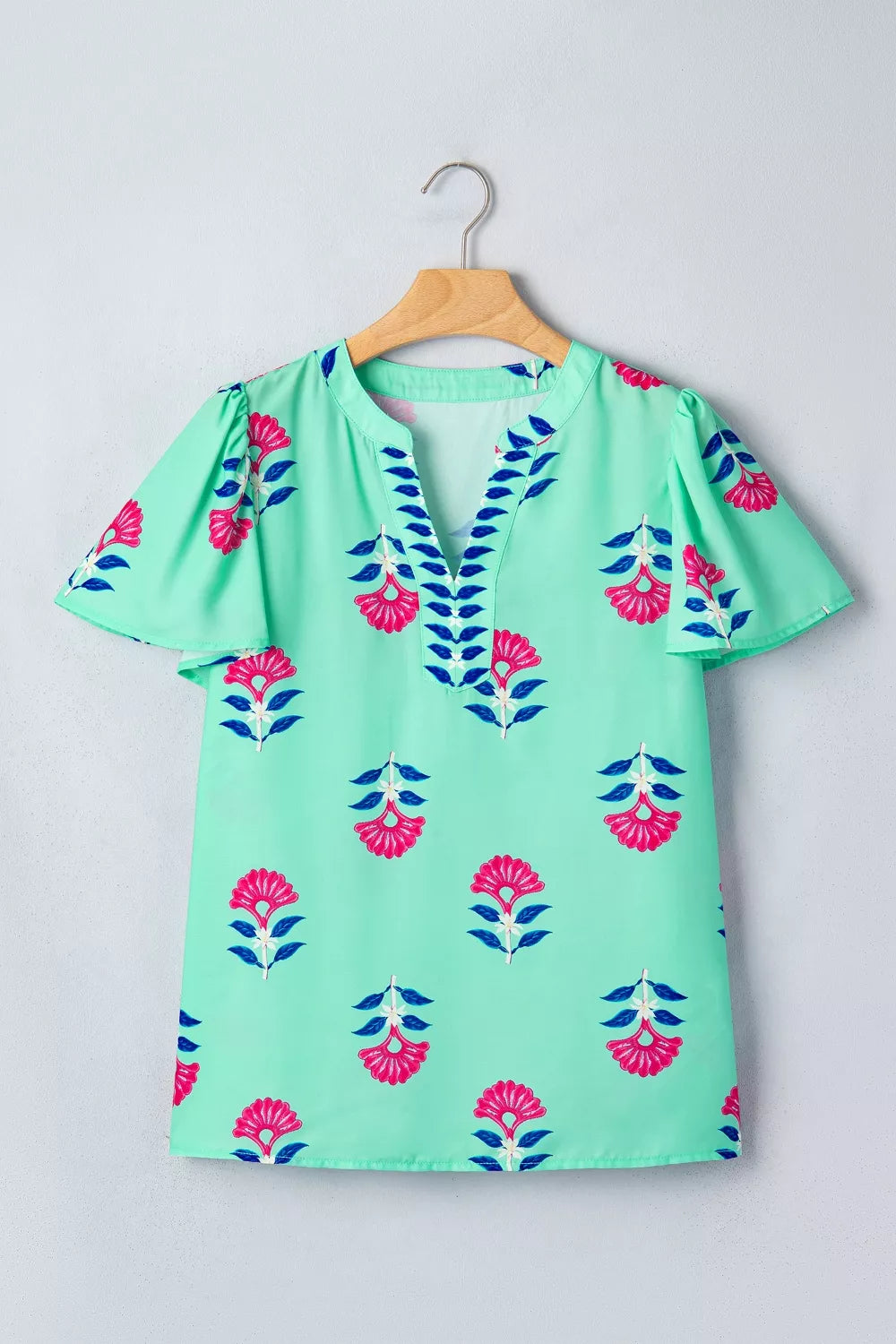 Mint green embroidered floral V-neck flutter sleeve blouse with blue leaf trim.