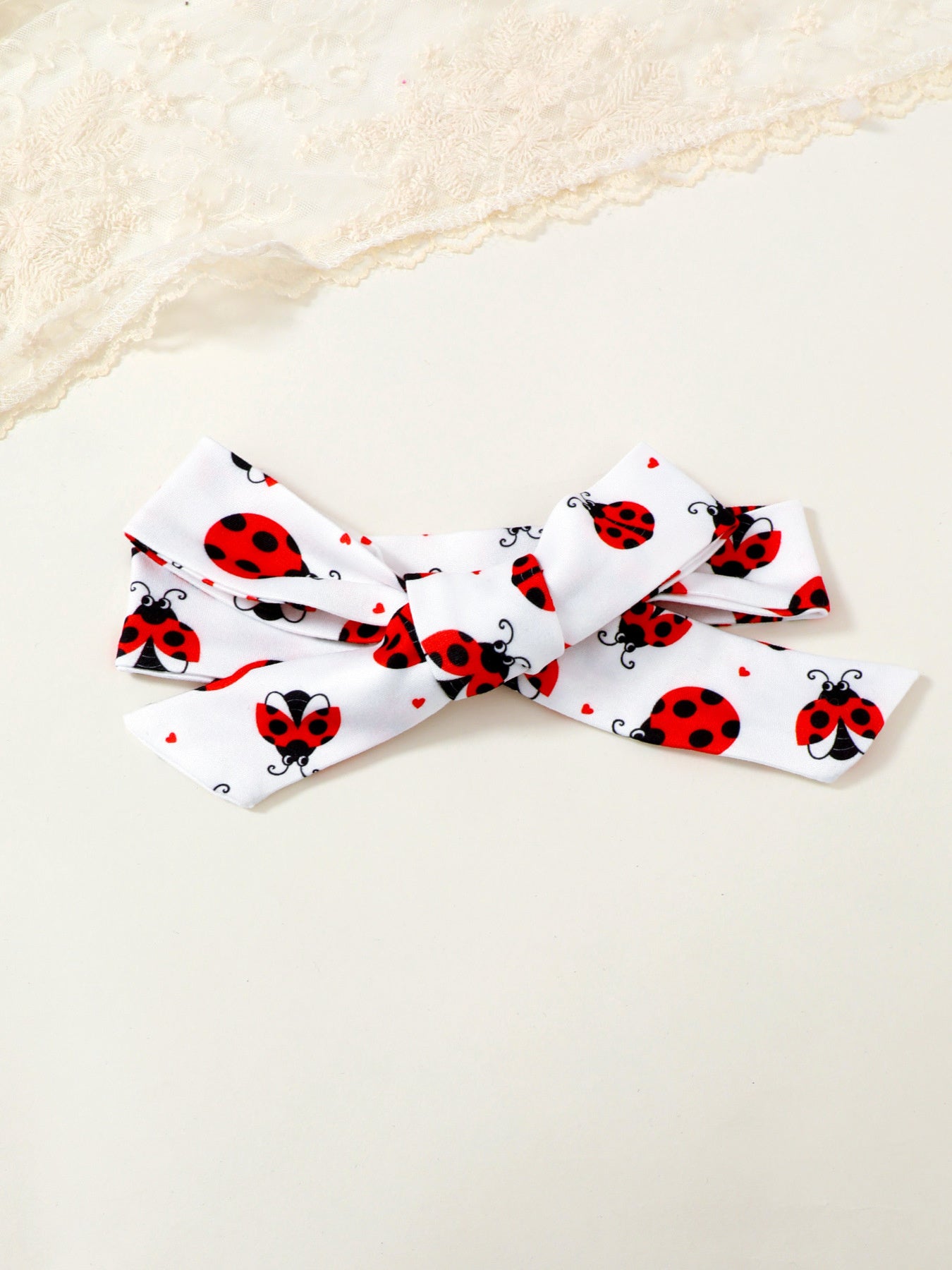 White baby headband with red ladybug print and bow detail