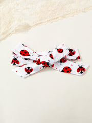 White baby headband with red ladybug print and bow detail