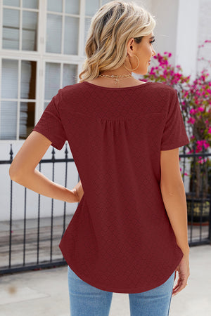 Rust eyelet yoke gathered henley shirt with short sleeves and a curved hem.