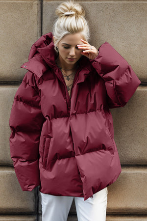 Burgundy oversized puffer jacket with hood and zip closure, featuring a relaxed fit and quilted design.