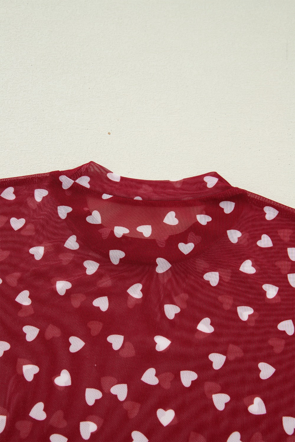 Deep red sheer t-shirt with white heart print and mock neck detail.