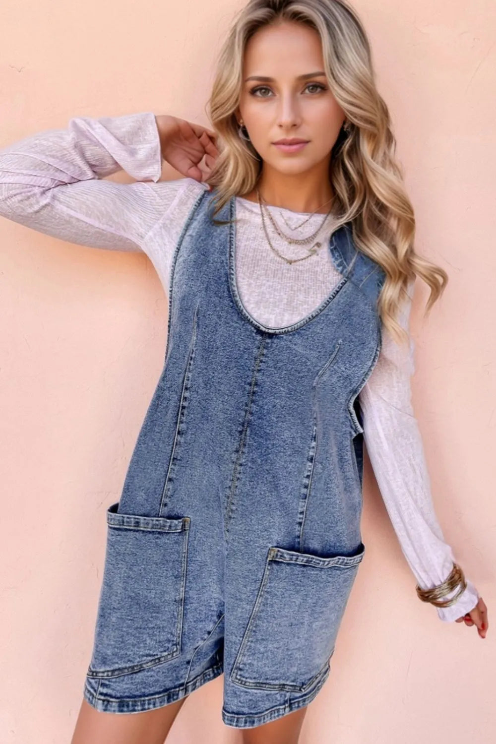 Acid wash denim romper with patch pockets and a scoop neckline.
