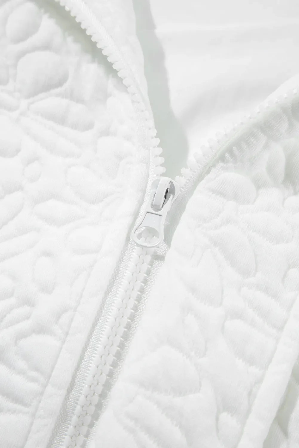 White bomber jacket with all-over quilted floral pattern and white zipper detail.