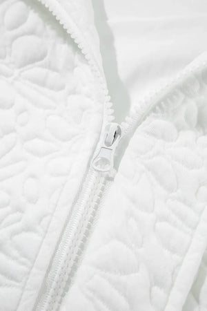 White bomber jacket with all-over quilted floral pattern and white zipper detail.