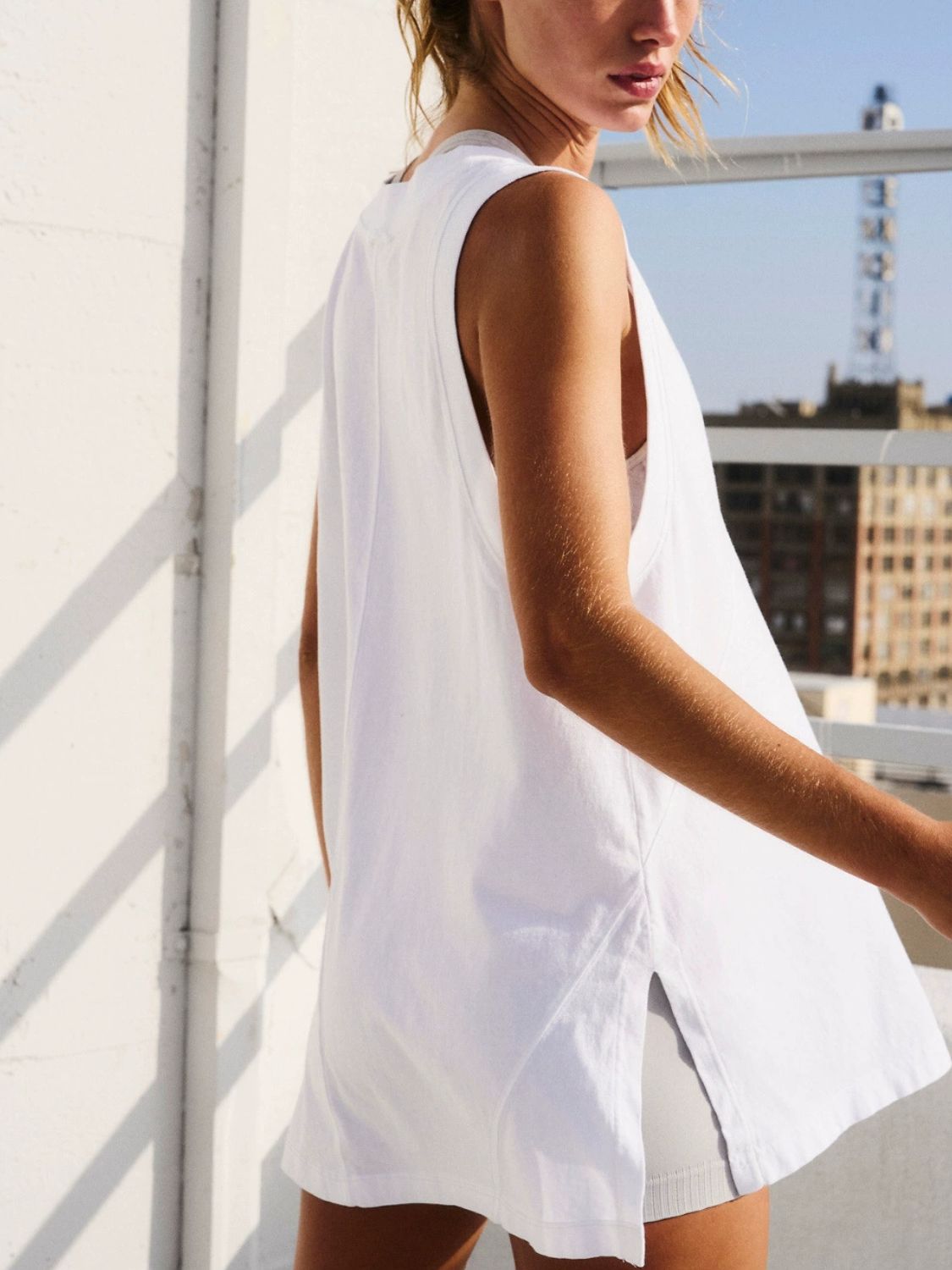 White wrap-front pocket tank top with side slits and a relaxed fit.