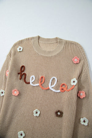 Khaki knit sweater with embroidered "hello" and floral appliques.