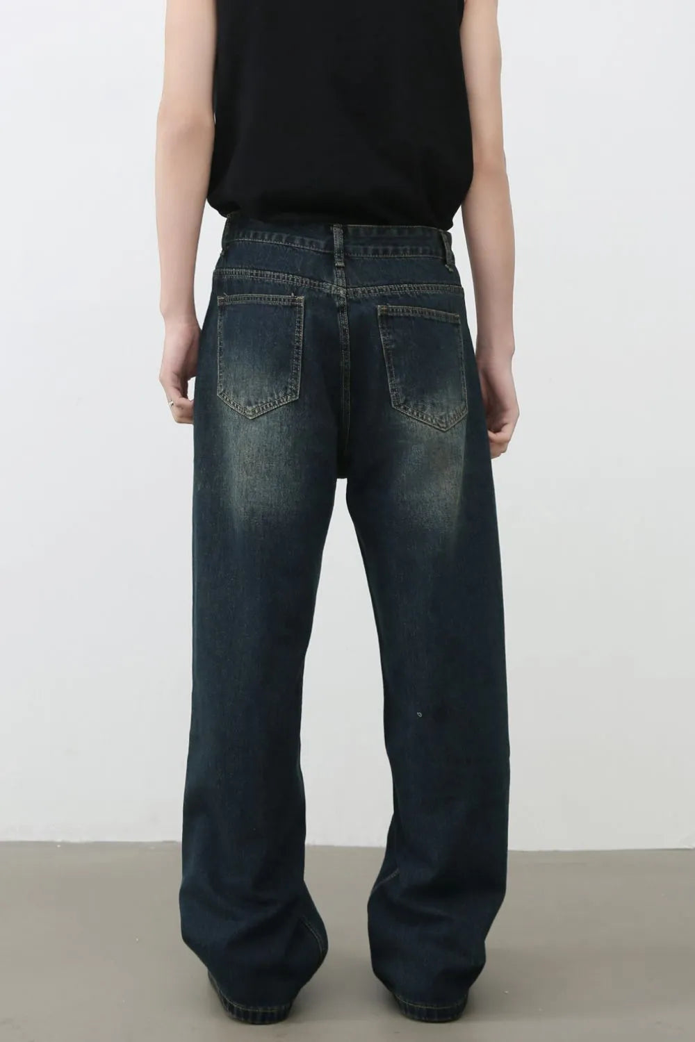Distressed dark wash wide-leg denim jeans with knee tears and a relaxed fit.